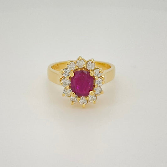 A yellow gold ring featuring an oval-cut ruby center stone surrounded by a halo of small diamonds.